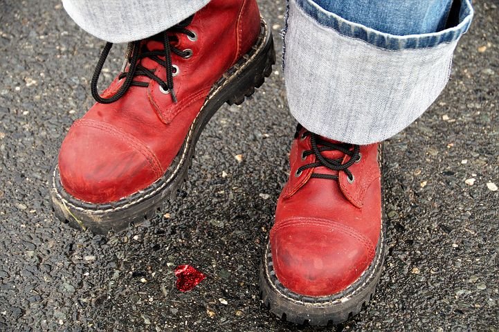 Ein paar Füße in roten Schuhen auf Asphalt