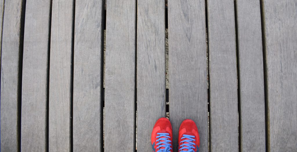 Rote Schuhspitzen auf grauen Holzplanken