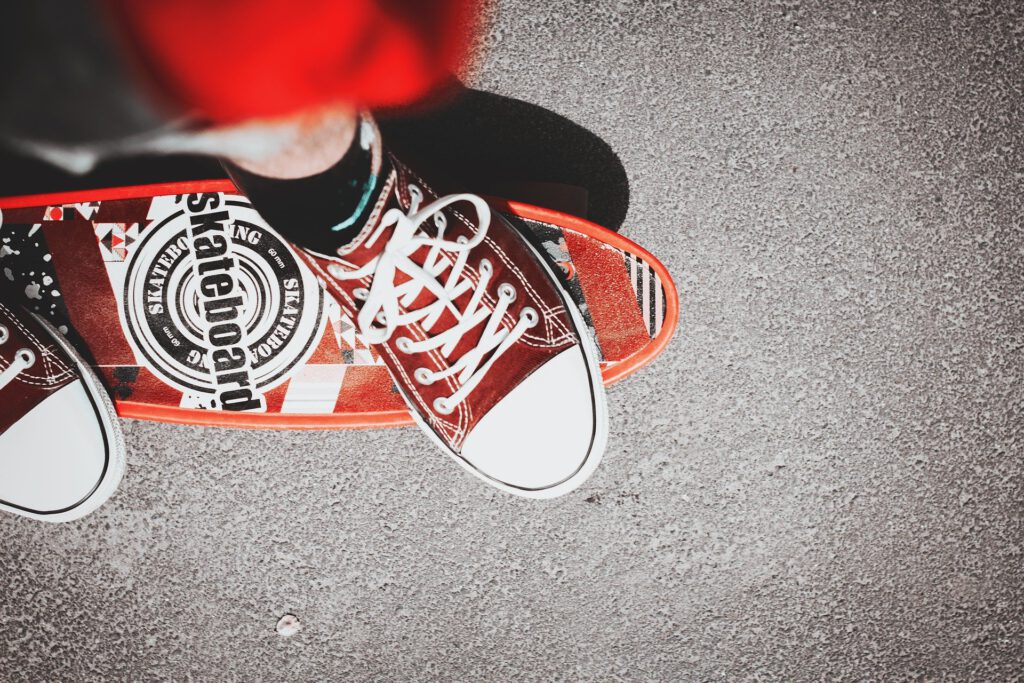 Füße in roten Turnschuhen stehen auf einem roten Skateboard